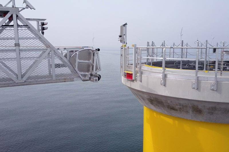 A gangway is approaching an offshore wind substructure.